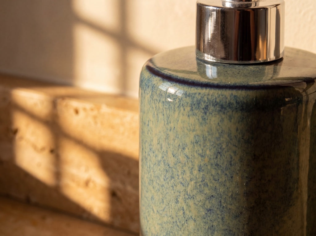 Macro close-up of the glossy blue-green reactive glaze, dark navy rim line and silver pump collar.