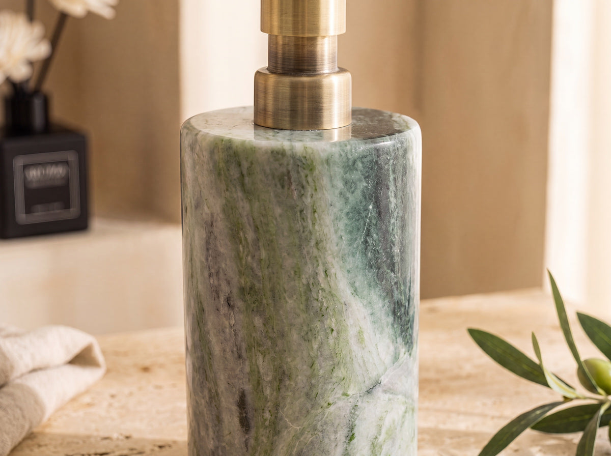 Close-up of emerald marble veining and the brushed brass pump base on a natural stone lotion dispenser.