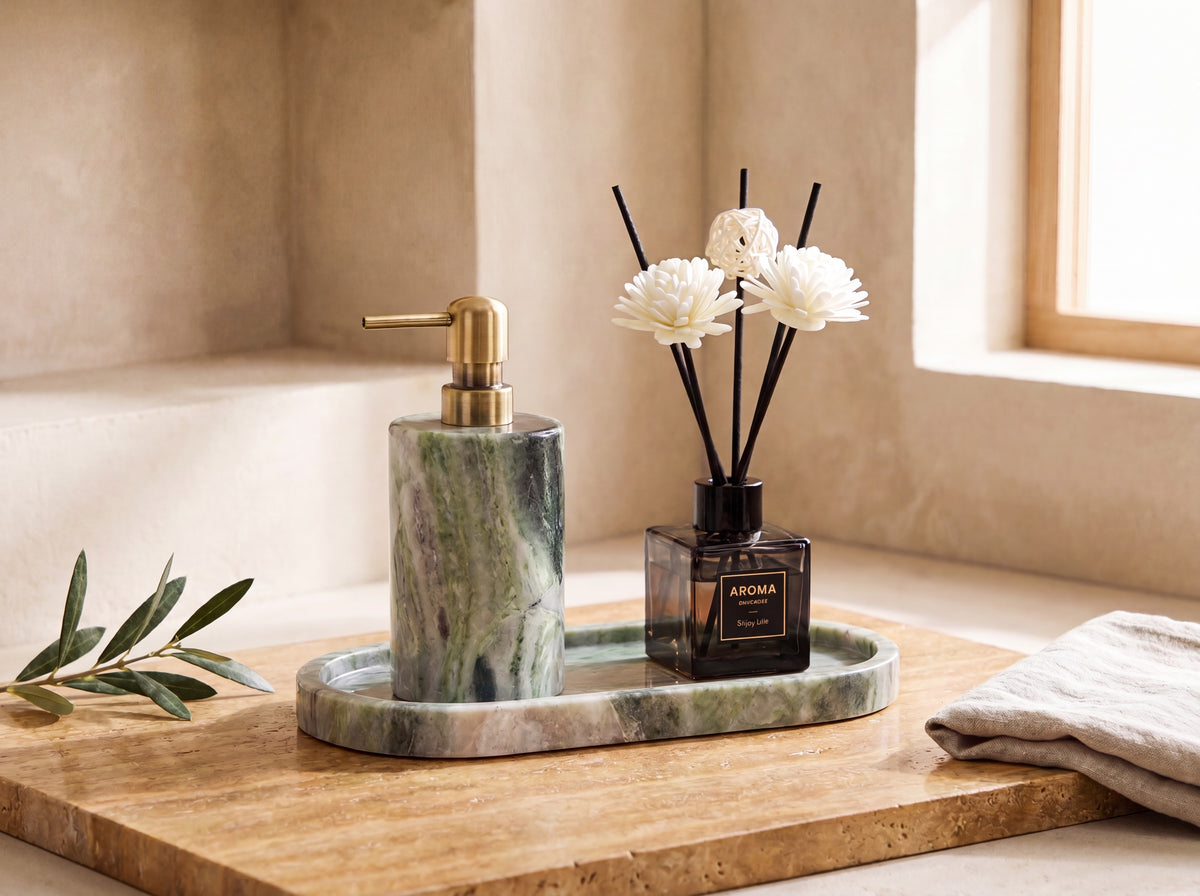 Green marble dispenser, tray and reed diffuser styled on a warm luxury bathroom vanity with linen and an olive stem.