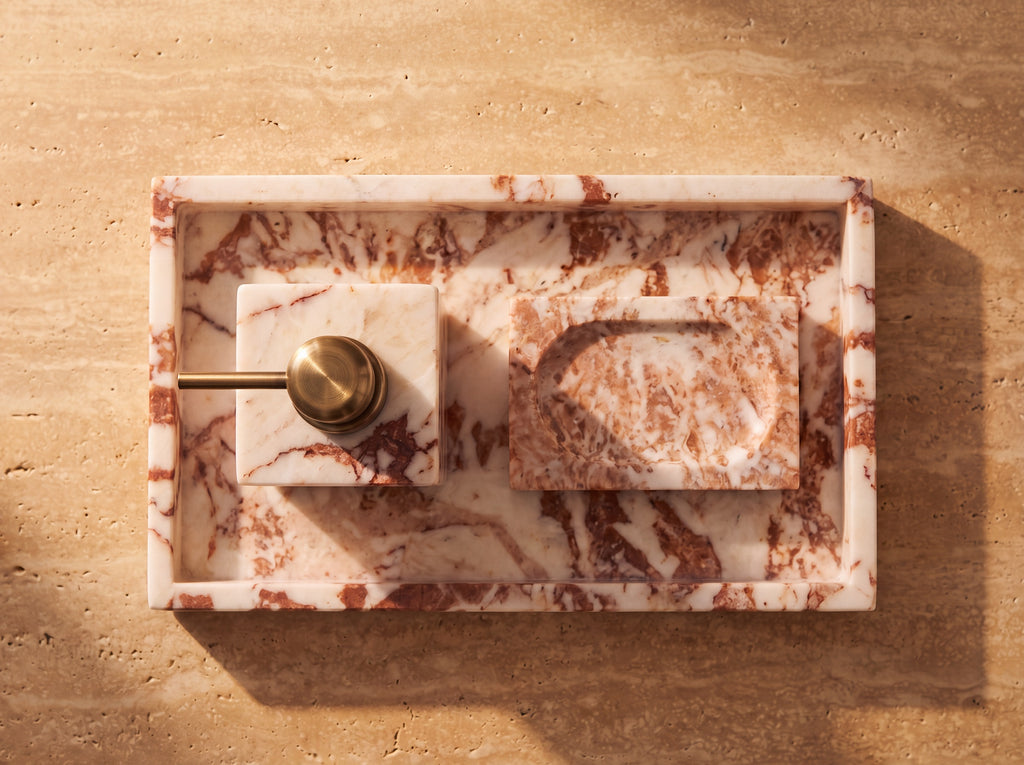 Overhead view of a marble tray holding a marble soap dispenser and a carved marble soap dish with a cream soap bar.