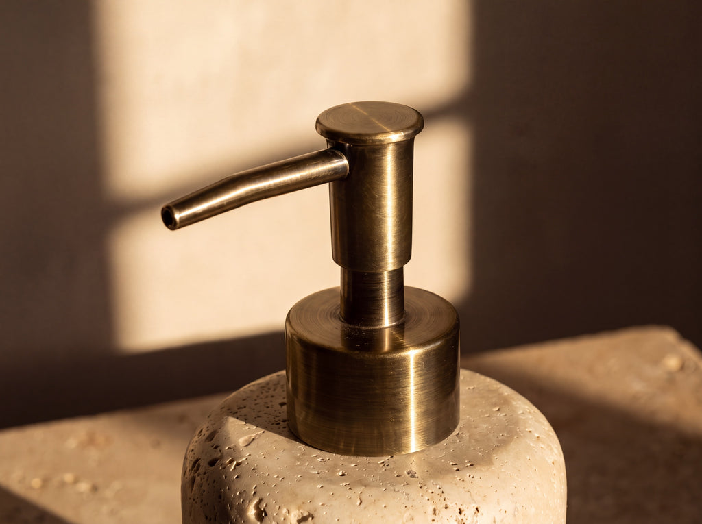 Macro of the antique brass pump head, stepped collar and long angled lever on the travertine dispenser
