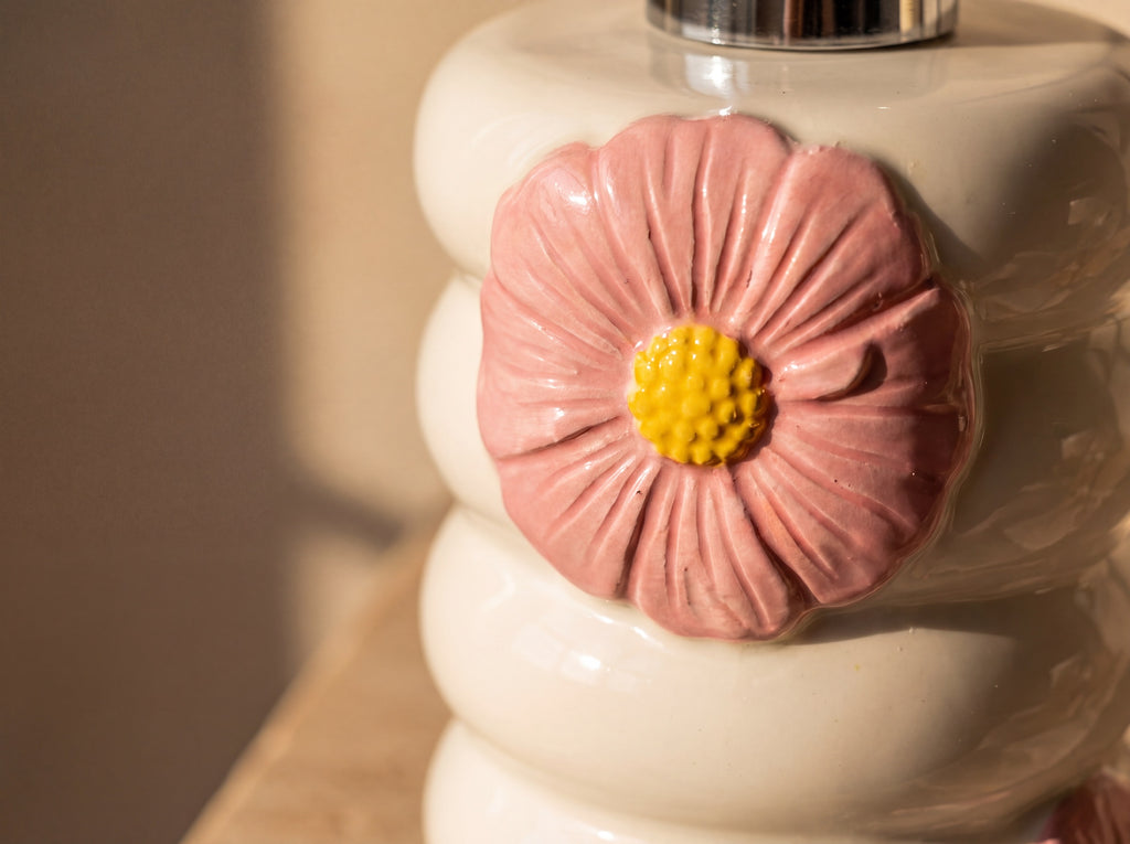 Macro close up of the sculpted pink flower with carved petal veins and a textured yellow centre on glossy white porcelain.