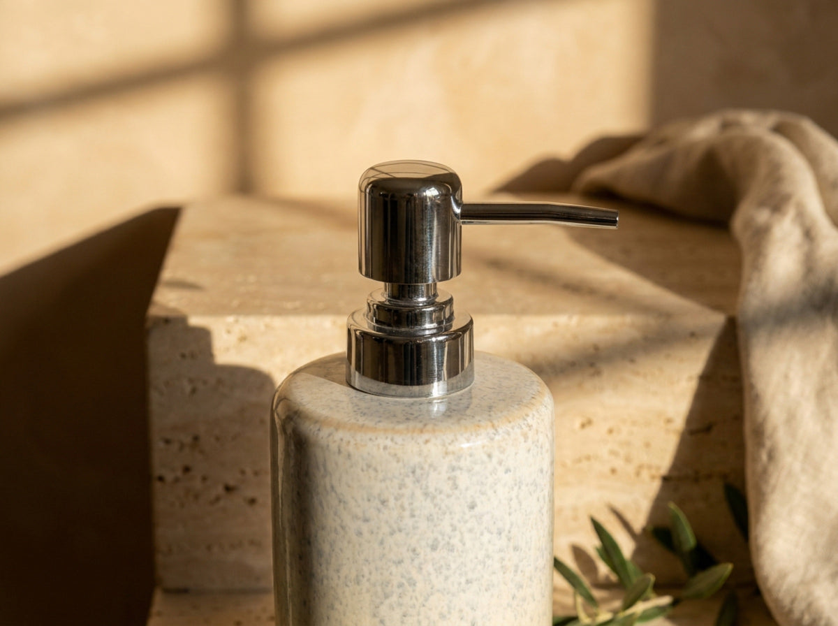 Close up of the polished chrome pump head, fluted collar and lever spout on the glazed ceramic dispenser.