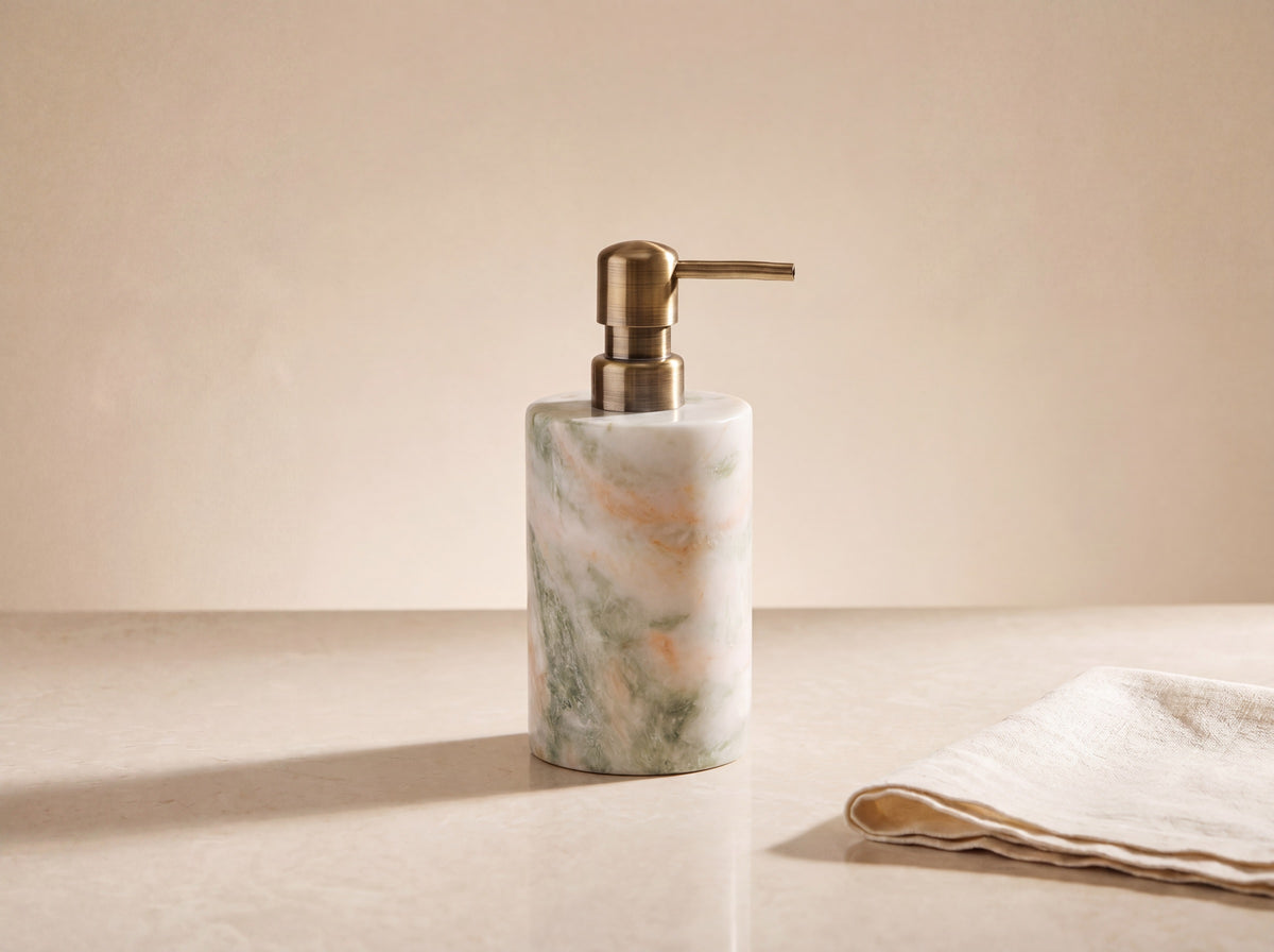 Single polished marble soap dispenser with antique brass pump on a honed cream stone surface