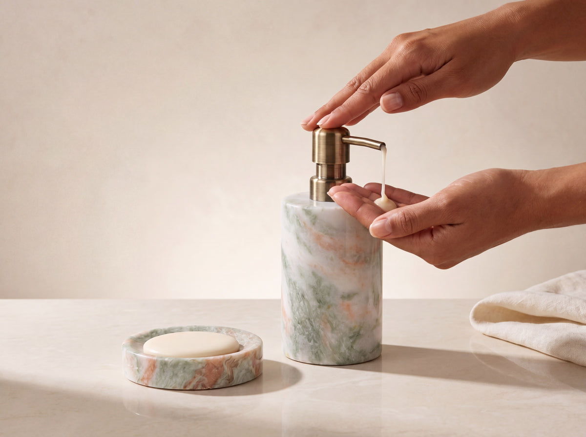 A woman's hand pressing the brass pump, dispensing soap into her palm beside the marble soap dish