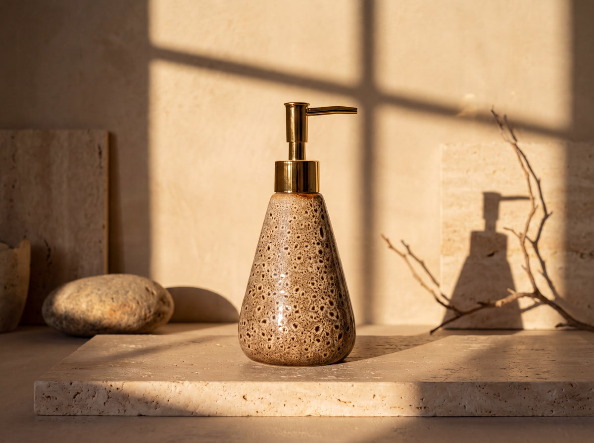 Front view of the spotted glaze ceramic soap dispenser showing its wide rounded base tapering to a gold pump.